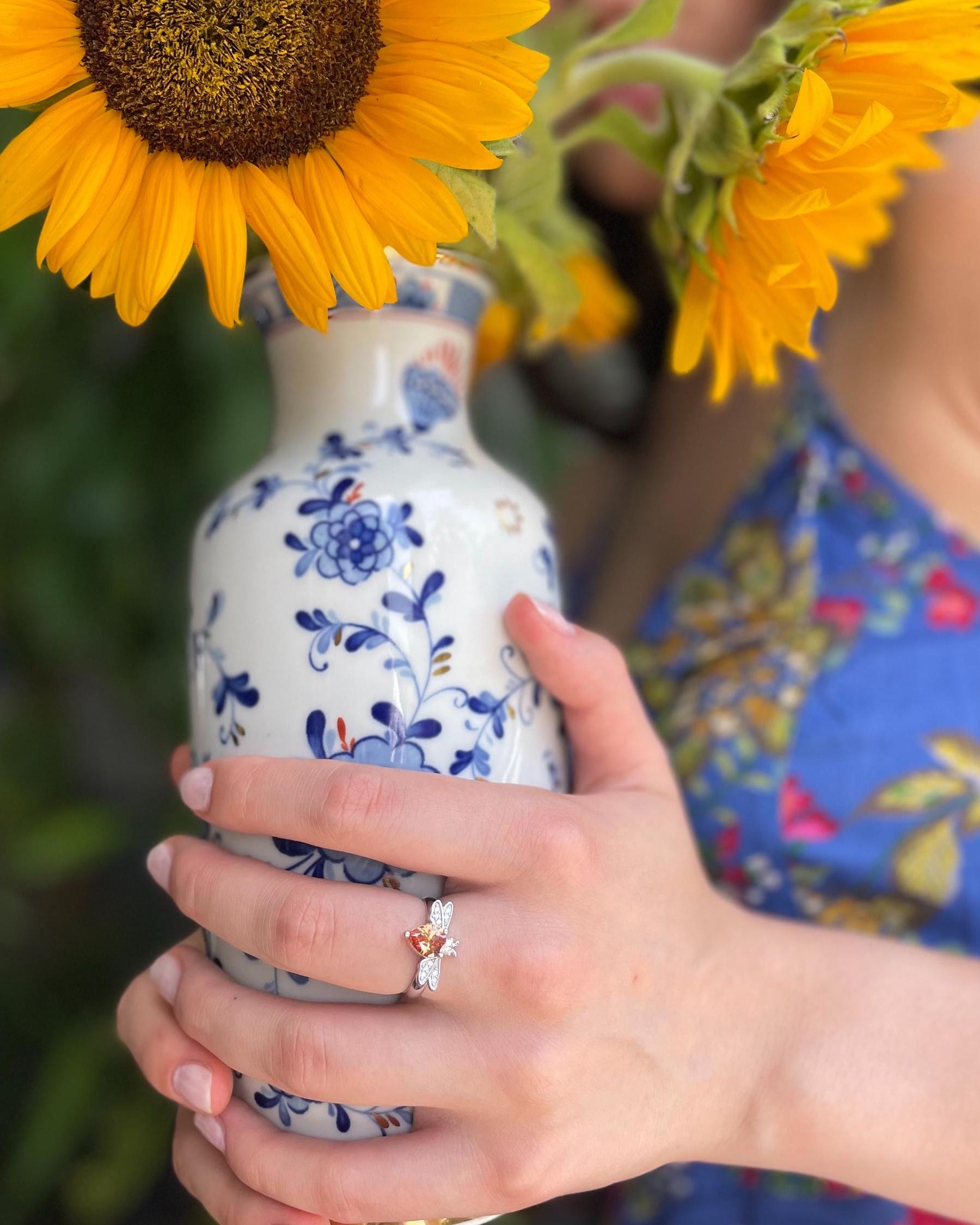 Person holding a blue and white floral-patterned vase with sunflowers.