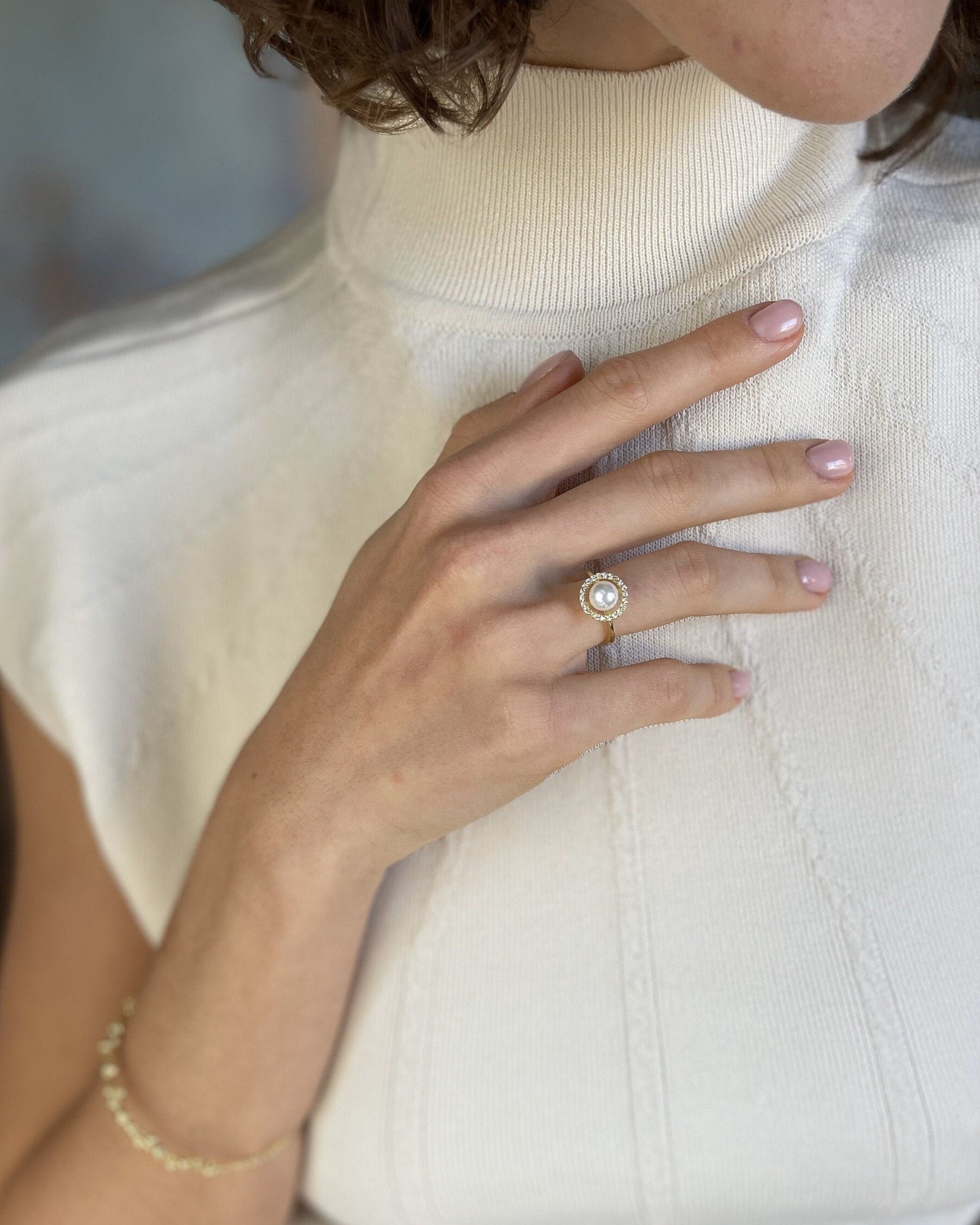 Close-up of a hand wearing a pearl ring on a white sleeve