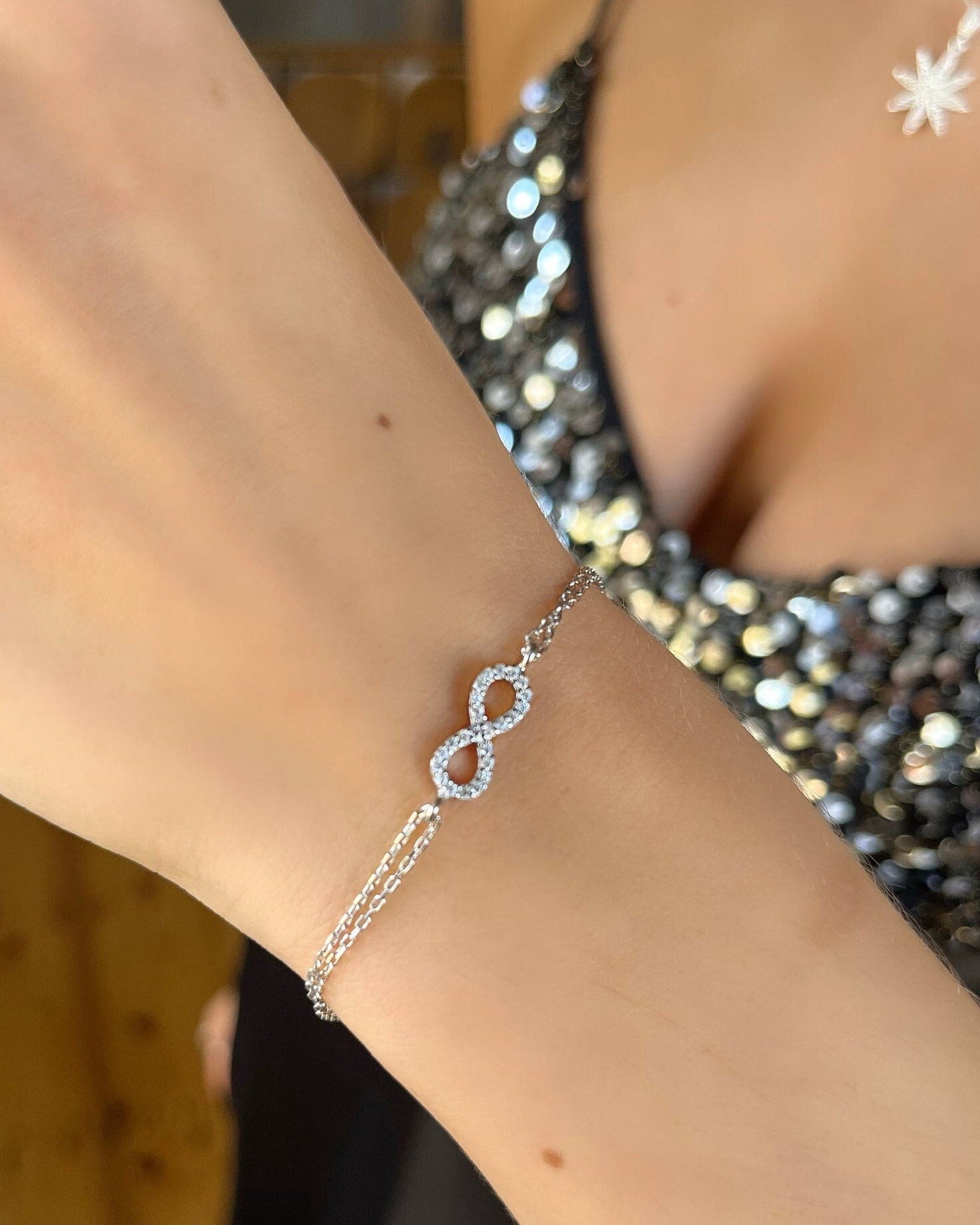 Silver bracelet with an infinity symbol on a person's wrist.