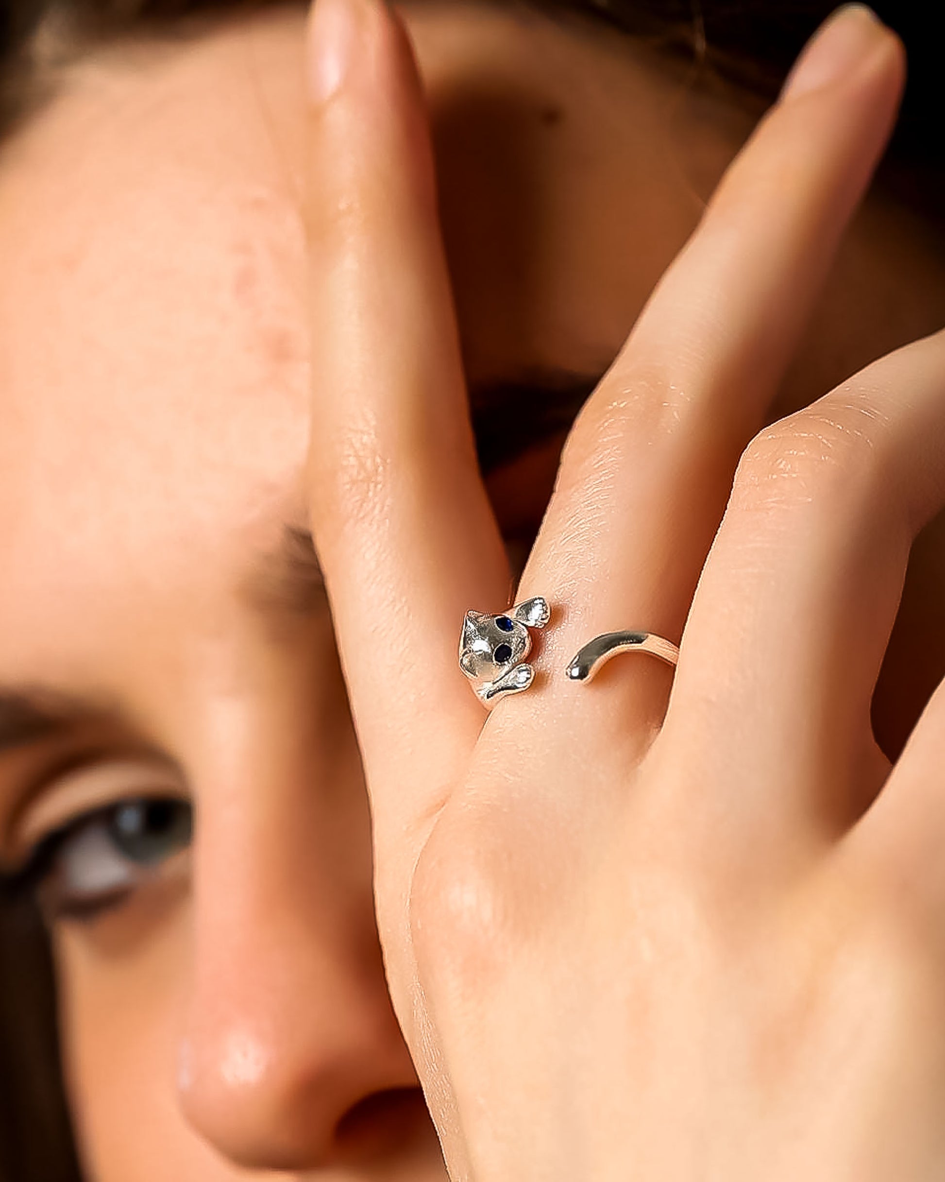 Close-up of a hand wearing a silver ring with a cat design.