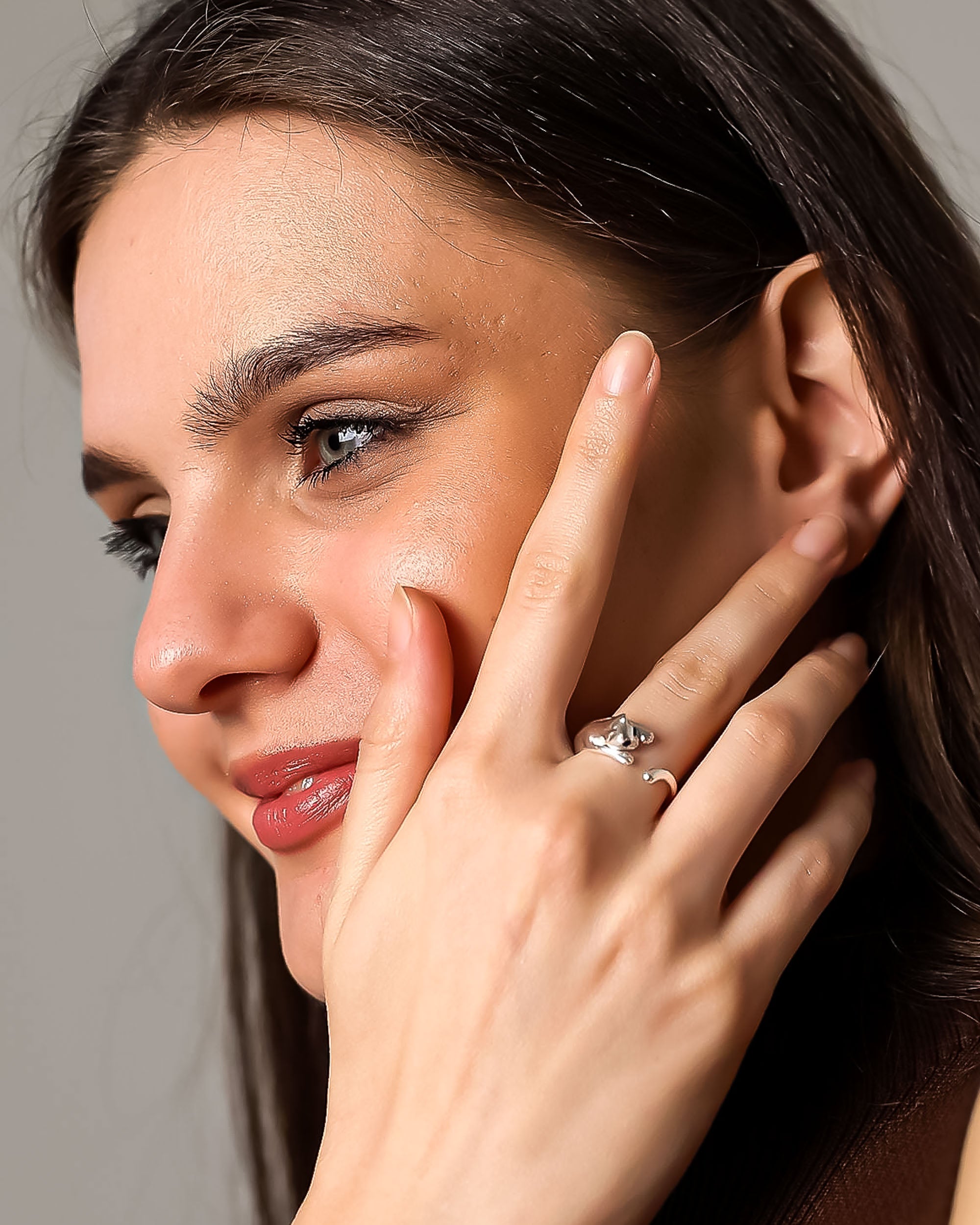 Woman applying makeup to her face with a neutral background