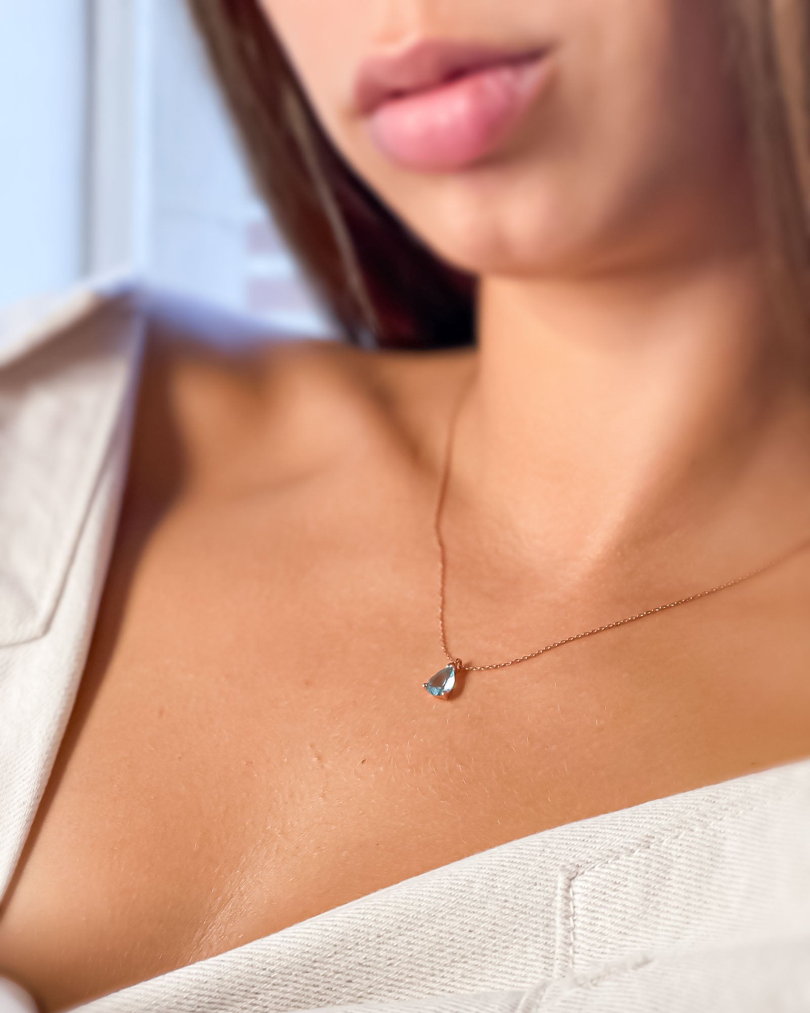 Close-up of a person wearing a delicate necklace with a small pendant.