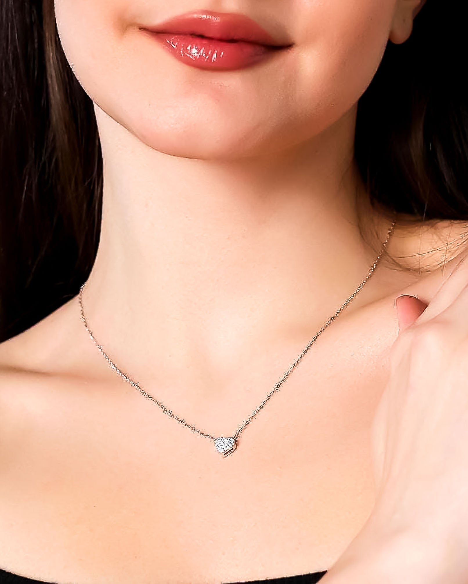 Close-up of a necklace with a heart-shaped pendant worn by a person.