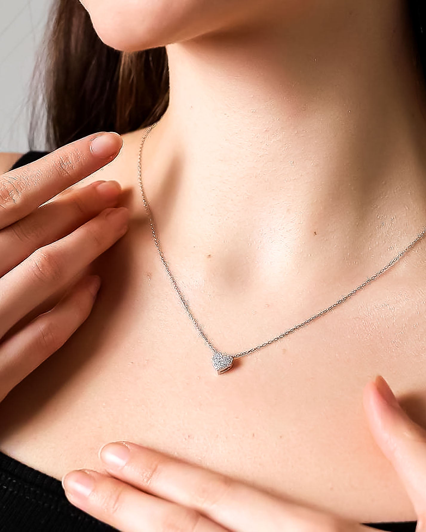 Necklace with a small pendant being worn and adjusted by hands