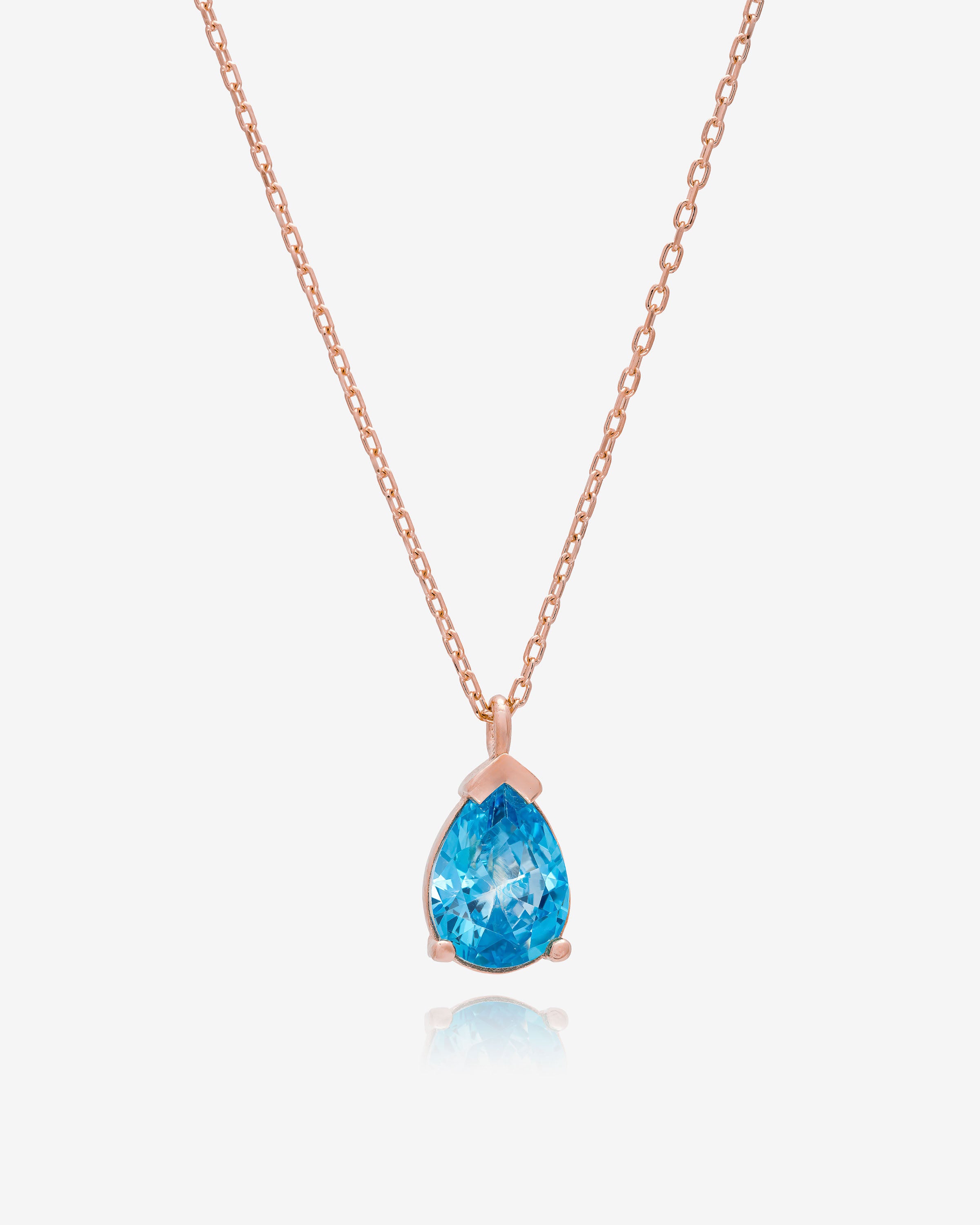 Rose gold necklace with a blue teardrop pendant on a white background