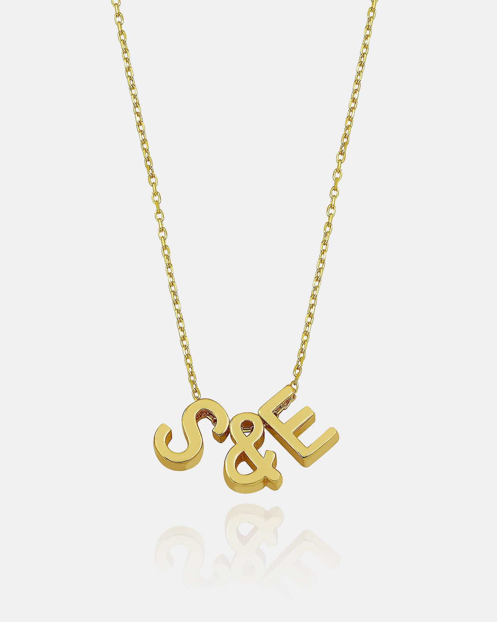 Gold necklace with 'S&E' letters on a white background