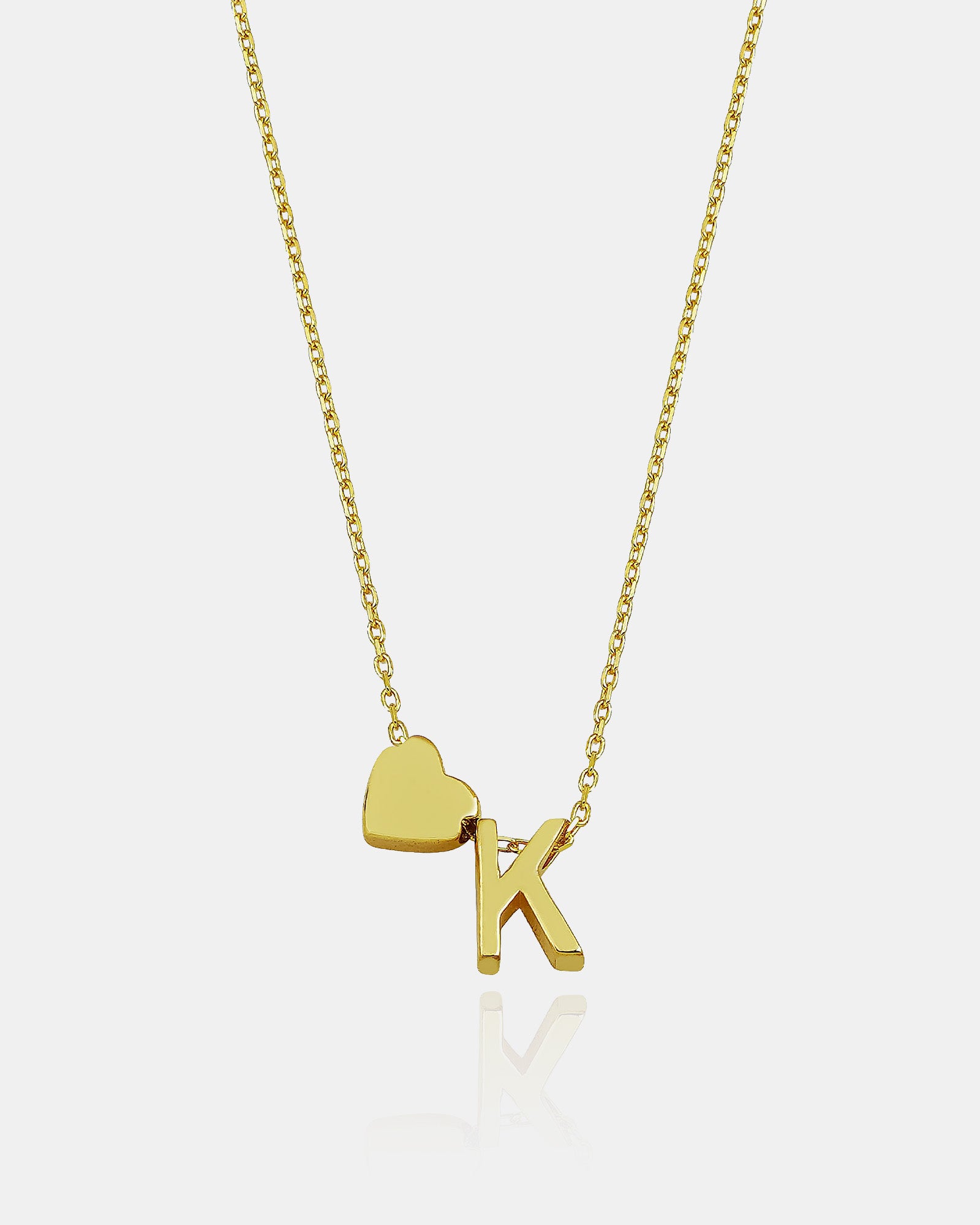 Gold necklace with a heart and 'K' pendant on a white background