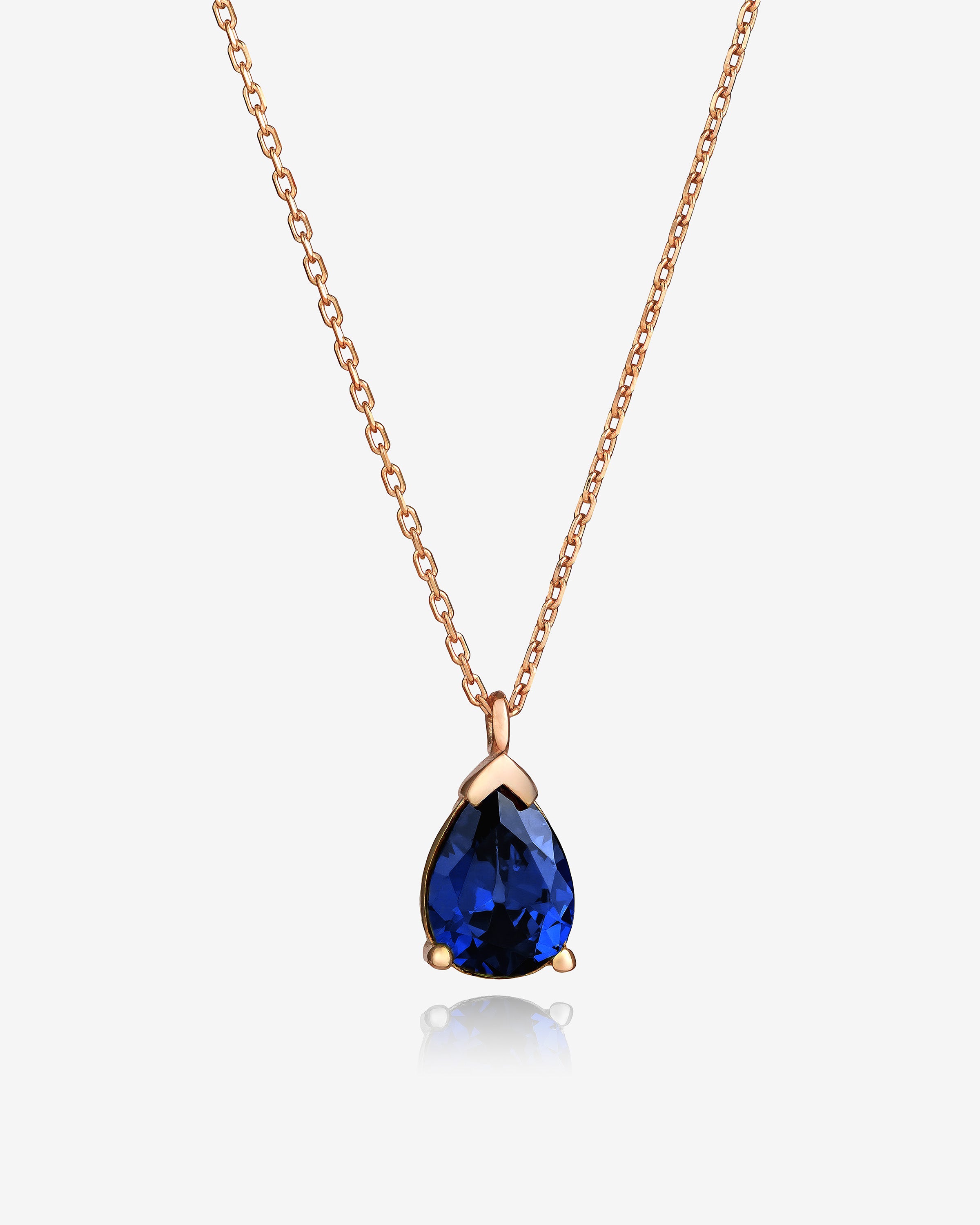 Rose gold necklace with a blue teardrop pendant on a white background